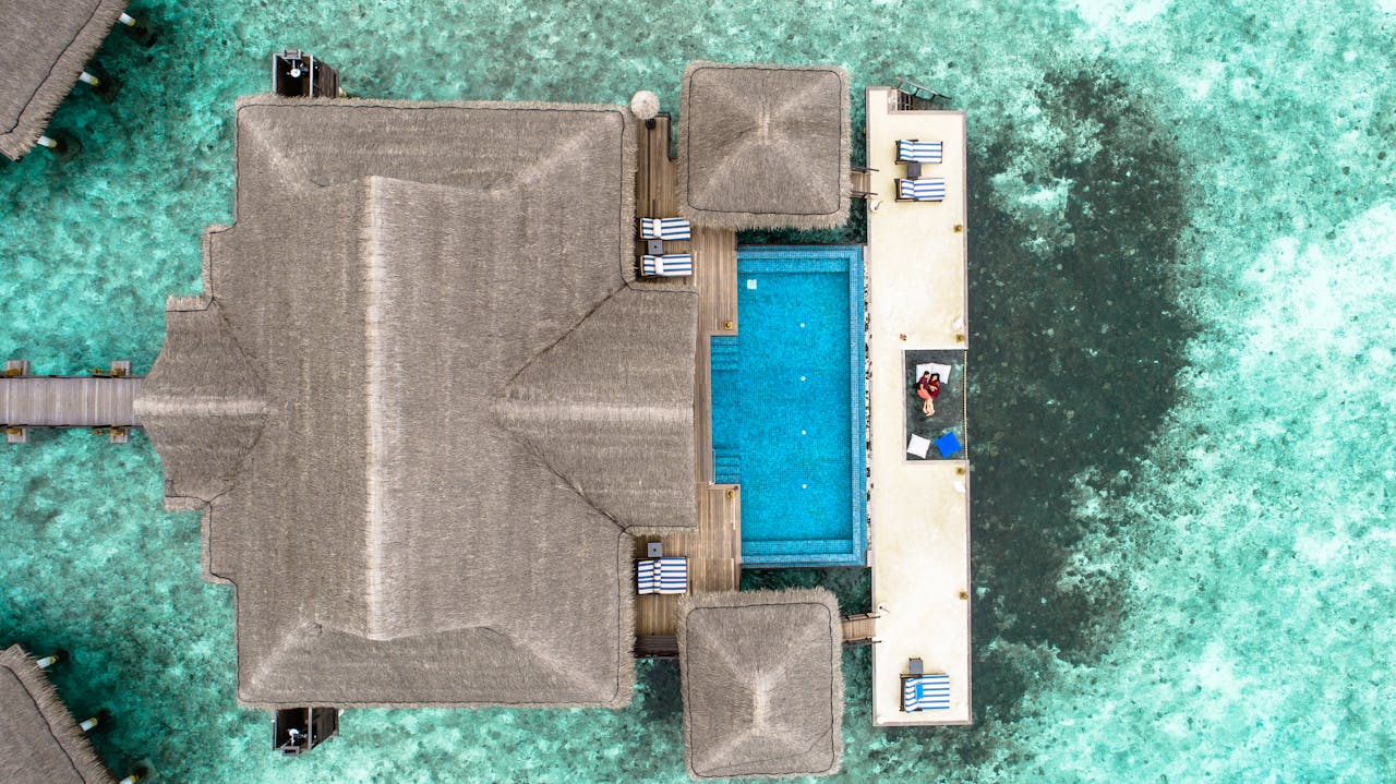 services-01 Stunning aerial view of a luxury villa with a swimming pool in the Maldives over turquoise waters.