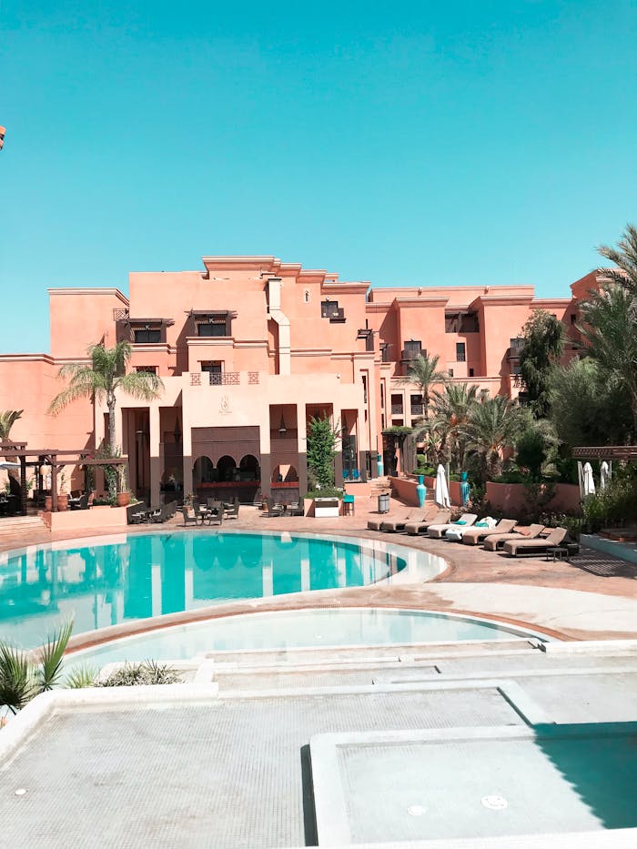 about-bg A luxury resort with palm trees and pool under clear blue skies.